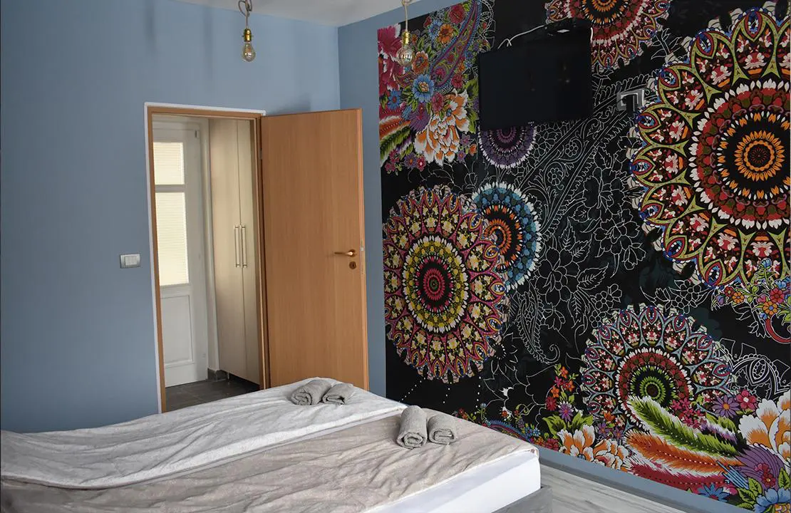 Spavaća soba sa bračnim krevetom i zidom ukrašenim šarenim mandala motivima